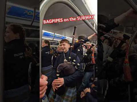 PipingBairn playing bagpipes in a subway carriage, from the video's official thumbnail.