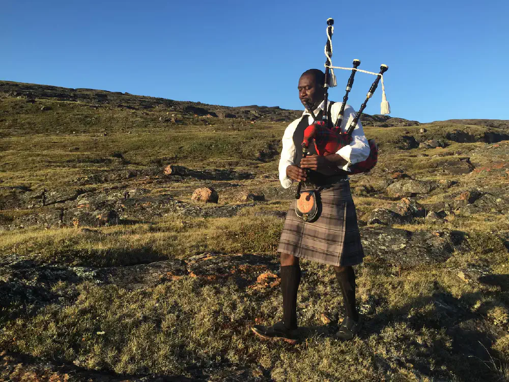 Sunday Thomas playing bagpipes outdoors in Nunavut.
